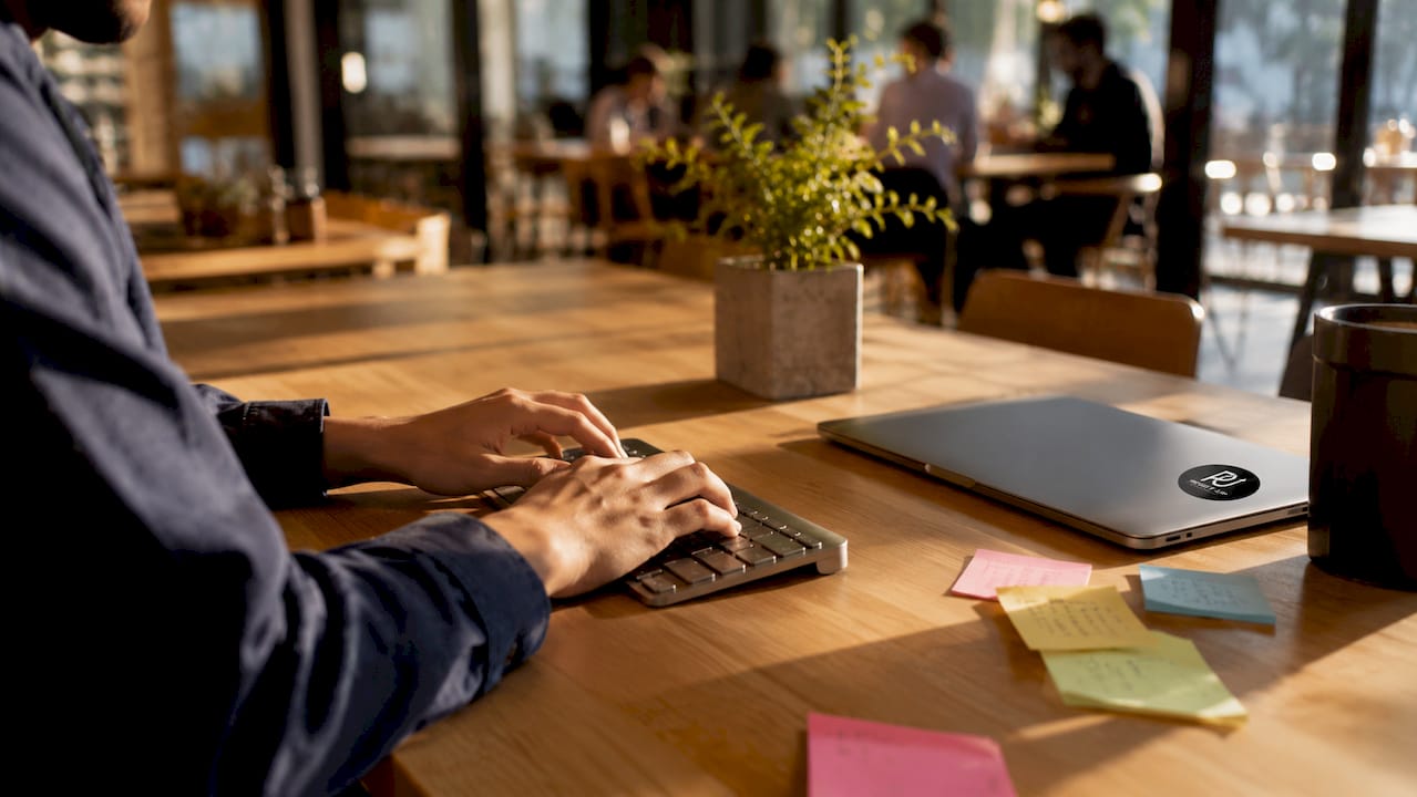 Hands typing on keyboard with office desk details